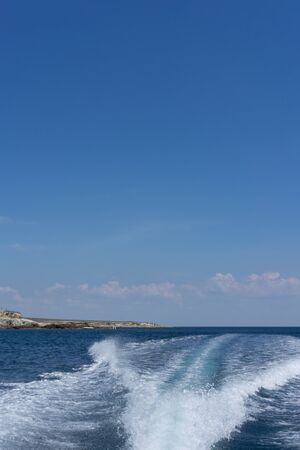 White foam trail from the movement of the boat on a blue background. Travel by sea.の写真素材
