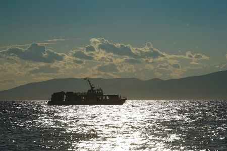 Silhouette of the ship against the seascape in the contra lightの写真素材