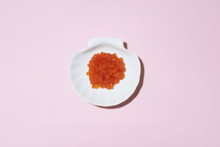 Porcelain plate with red caviar on a pink background.の写真素材