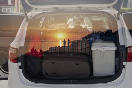 Double exposure of the car with things for traveling and sunset with silhouettes of people.の写真素材