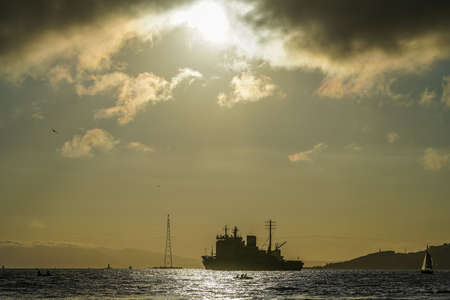 Seascape with a view of the silhouette of the city and the ship on the background of the sunset. Vladivostok, Russiaの写真素材
