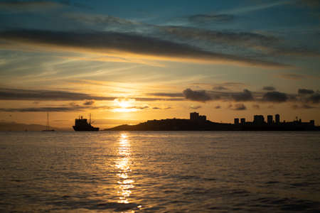 Seascape with a view of the silhouette of the city and the ship on the background of the sunset. Vladivostok, Russiaの写真素材