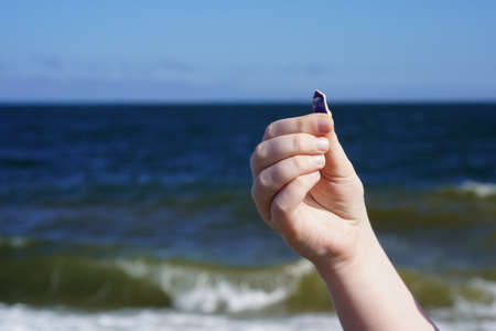 Child's hand with sea glass on the sea background. Glass beach, Vladivostokの写真素材