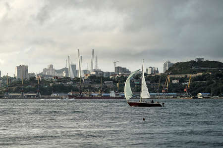 Seascape with the silhouette of a yacht on the background of the city. Vladivostok, Russiaのeditorial素材