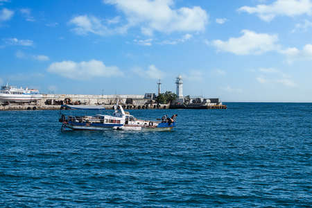 Yalta, Crimea-June 8, 2021: Seascape with a view of the boat on the background of the pier and the lighthouseのeditorial素材