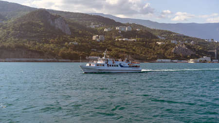 YALTA, Crimea-June 12, 2021: Seascape with a view of a pleasure boat on the background of the cityのeditorial素材