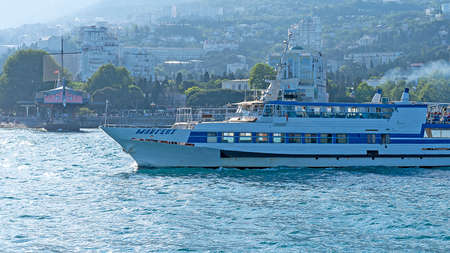 YALTA, Crimea-June 12, 2021: Seascape with a view of a pleasure boat on the background of the cityのeditorial素材