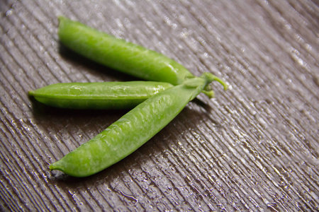 three pods of green peas on a brown backgroundの写真素材