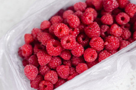 Fresh juicy Raspberries on the table. close up raspberry in the container. autumn harvest. healthy food. Pink ripe berries, sweet natural diet snackの写真素材