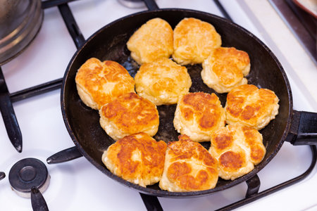 Russian sweet baked food. Fried pancakes on black modern pan close up.