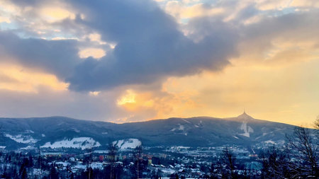 A stunning sunset beautifully illuminating the snowy mountains beneath the dramatic, swirling clouds...