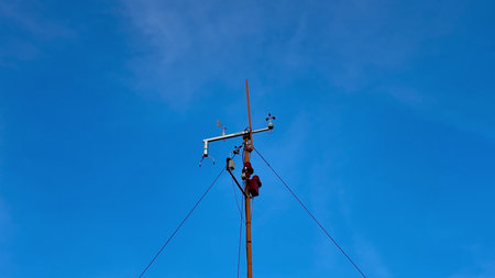 A highly skilled technician performs essential maintenance work on a utility pole against a bright...