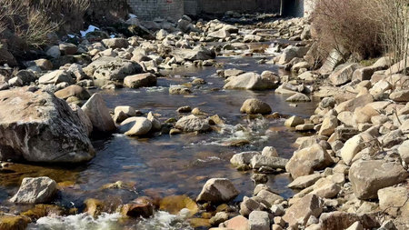 The scene shows a beautiful river winding between large rocks in a peaceful, serene natural setting