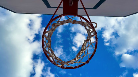 A vibrant and colorful view of a basketball hoop standing tall against a picturesque blue sky filled...