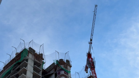 A contemporary building currently under construction that features a crane, showing intricate...