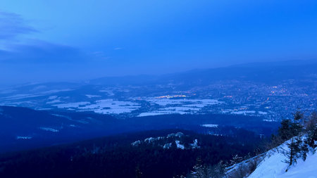 Evening winter landscape of the city and snow-capped mountains from the observation deck. High...
