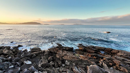 Experience a breathtaking view of the ocean waves powerfully crashing against the rocky coast at...
