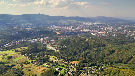 An aerial shot reveals a captivating mix of lush nature and urban areas beneath a clear, vibrant...