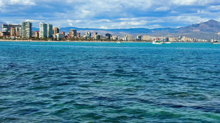 A stunning seaside view of a vibrant city set along a serene coast with mountains in the background