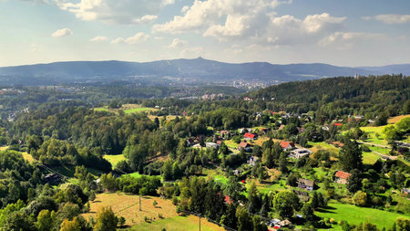 A stunning view of a green valley, surrounded by hills and charming homes, all under a bright sunny...