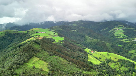 A stunning aerial landscape beautifully showcasing vibrant green hills positioned under a cloudy sky...