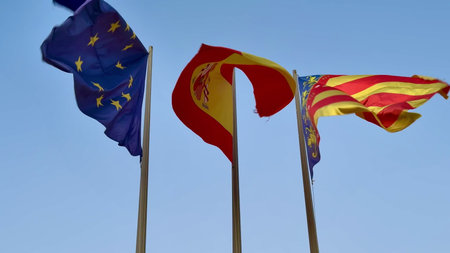 The colorful flags of Europe, Spain, and Catalonia wave beautifully in the gentle breeze against a...