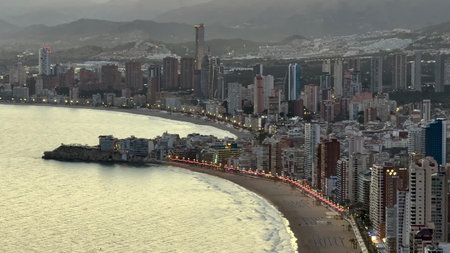 A picturesque view of a modern coastal city with illuminated skyline and tranquil waters during...