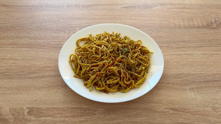 A delightful plate of well-flavored stirfried noodles, featuring a variety of vibrant spices and...