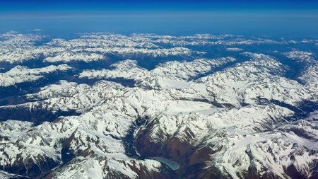 This breathtaking aerial view showcases stunning and majestic snowcovered mountain peaks beneath a...