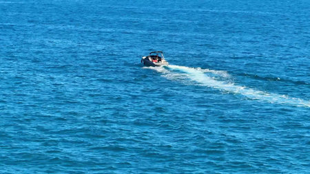 A speedboat races across stunning blue waters under a clear sky, perfect for unforgettable summer...