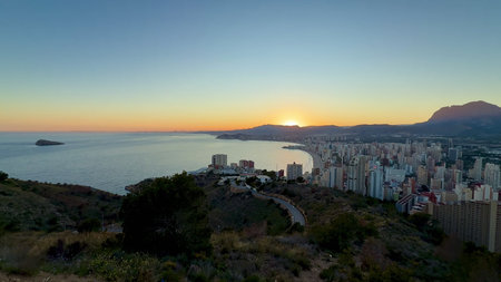 The breathtaking view of a stunning sunrise casting golden hues over the coastal city and majestic...