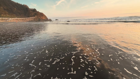 A beautifully serene view of gentle ocean waves gracefully rolling in under a spectacular colorful...
