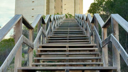 A wooden stairway leads to a modern concrete tower, surrounded by lush greenery that enhances the...