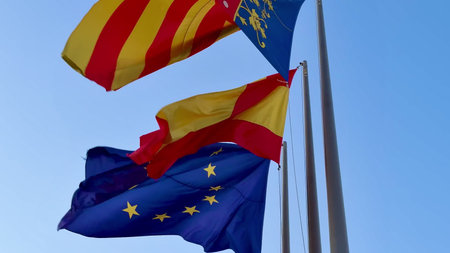 Colorful and vibrant flags representing Spain, Catalonia, and the EU flutter gracefully in the soft...
