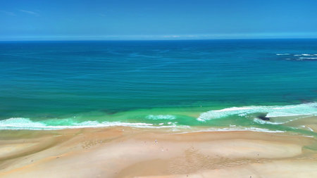 Breathtaking aerial scenery capturing the tranquil beauty of a sandy beach meeting the vibrant...