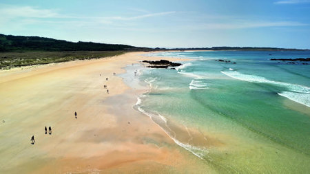 An aerial view showcasing a stunning beach where people are having a great time in the sun and enjoying the wavesの写真素材