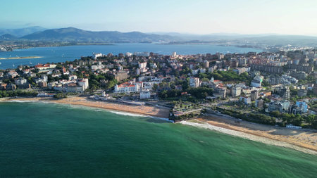 Enjoy the stunning aerial view of a picturesque coastal town with beautiful beaches and majestic mountainsの写真素材