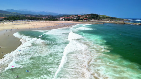 A vibrant beach scene filled with beautiful rolling waves, cheerful sunbathers, and stunning scenic views all aroundの写真素材