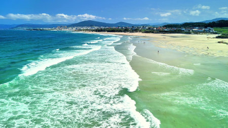 Aerial photo capturing breathtaking views of serene beach waves and coastline under clear blue skiesの写真素材