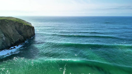 Immerse yourself in the tranquil beauty of flowing ocean waves and lush green cliffs in this...