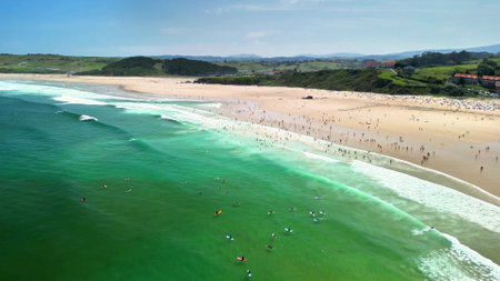 Stunning aerial shot showcasing a vibrant beach scene filled with surfers and sunbathers under clear skies.の写真素材