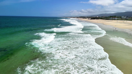 Experience beautiful coastal scenery with gentle waves and sandy shores under a clear blue sky, inviting relaxationの写真素材