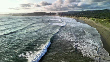 Experience the remarkable tranquility of ocean waves gently meeting the shore during a stunningly beautiful sunsetの写真素材