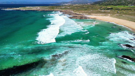 A breathtaking aerial shot showcasing vibrant turquoise waves meeting beautiful sandy shores and lush greeneryの写真素材