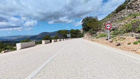 A picturesque mountain road surrounded by lush greenery and vibrant skies, perfect for travel footage.の写真素材