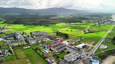Stunning aerial drone footage presents a breathtaking view of lush green fields alongside modern architectureの写真素材