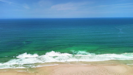 A beautifully tranquil beach scene showcasing stunning turquoise waters and soft gentle waves beneath a clear blue skyの写真素材