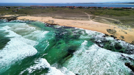 Experience the breathtaking and stunning aerial views of vibrant coastal waves crashing onto serene beachesの写真素材