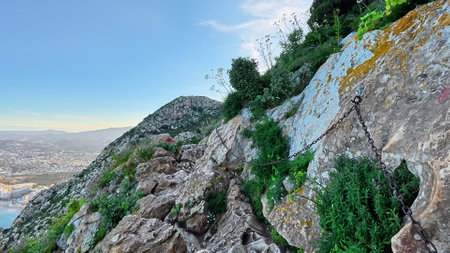 Enjoy breathtaking mountain trail views that feature lush greenery along with safety chains for your protectionの写真素材