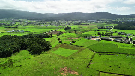 A truly stunning aerial capture beautifully showcasing the vibrant farmland and picturesque rural settlements belowの写真素材